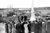 Armistice ceremony at Portlethen Church War Memorial; possibly post war 1940's or early 1950's. The four timber receiver towers and one of the taller steel transmitter fowers of RAF Schoolhill are seen on the horizon