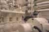 The air conditioning plant room showing one of two 3 cylinder compressors. These compress the refrigerant (originally the toxic anaesthetic liquid, Methyl Chloride). Mounted on the wall behind there are two cylindrical horizontal tanks where the cooled water from the air cooled heat exchangers cools the refrigerant (Nick Catford)