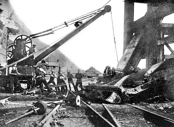 Demolition of Borehole shaft head at Shakespeare Colliery underway probably in 1928. The railway cottages and bungalow are seen in the background. They were eventually vacated and demolished in the 1960s (White Cliffs Countryside Partnership)