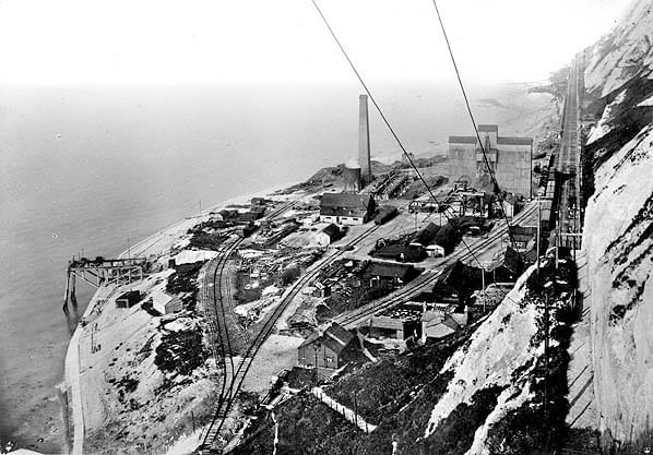 Looking west from Akers steps c1903. No.2 Pit (Simpson) headframe has been substantially rebuilt and is now enclosed in a large wooden building. No.3 Pit (Borehole) is seen in front, also with a new headframe. The colliery landing stage is seen on the left. Shaft linings arrived here by barge from Admiralty Pier (White Cliffs Countryside Partnership)
