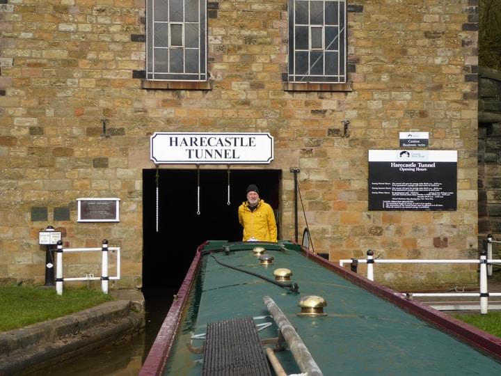 Narrowboat Dragonfly with Sub Brit Chairman Martin Dixon at the helm emerging from the south portal of the Harecastle canal tunnel built by Telford.  The white chains indicate the lowest profile of the tunnel which has reduced over the years due to subsidence. These chains have now been replaced by a fixed profile board as part of safety improvements following a fatality in 2014 when a boater was knocked overboard in the lowest section of the tunnel. The building surrounding the portal contains fans for ventilation purposes.  (Linda Dixon)