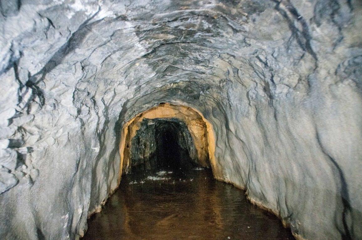 View inside the canal tunnel with lots of water dripping down! The first bit of the tunnel is grey because it is concrete shot blasted. There's a middle bit which is orange in colour - this is probably because of some iron deposits. Beyond that is an unlined section of tunnel which is much darker than the rest.