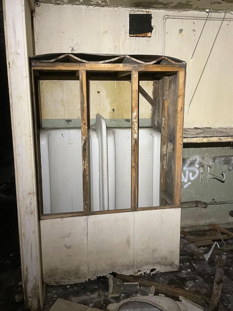 Some older style men's urinals that had been boxed over when the room was converted to a kitchen (Neil Iosson - 2021)