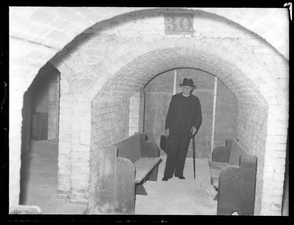 Rev. E.O. Gittens the new priest at Holy Trinity Church, Oxford Road, Reading in the church vaults. (1939) (Reading Museum (Reading Borough Council))