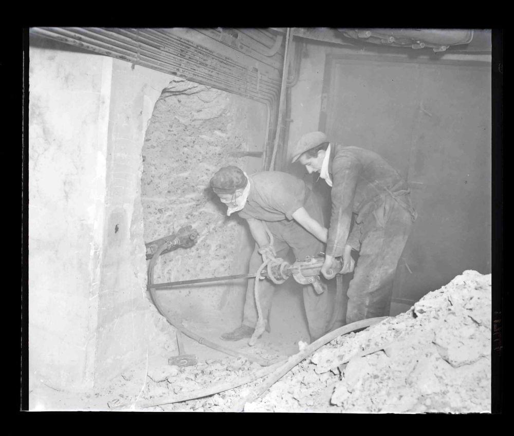 Kingsway Telephone Exchange, Holborn, Tunnel Scheme 2147 construction: base of old west shaft. Drilling through concrete headwall to connect with 7 foot diameter ventilation tube. (1952) (www.digitalarchives.bt.com - TCB 417/E 17664)